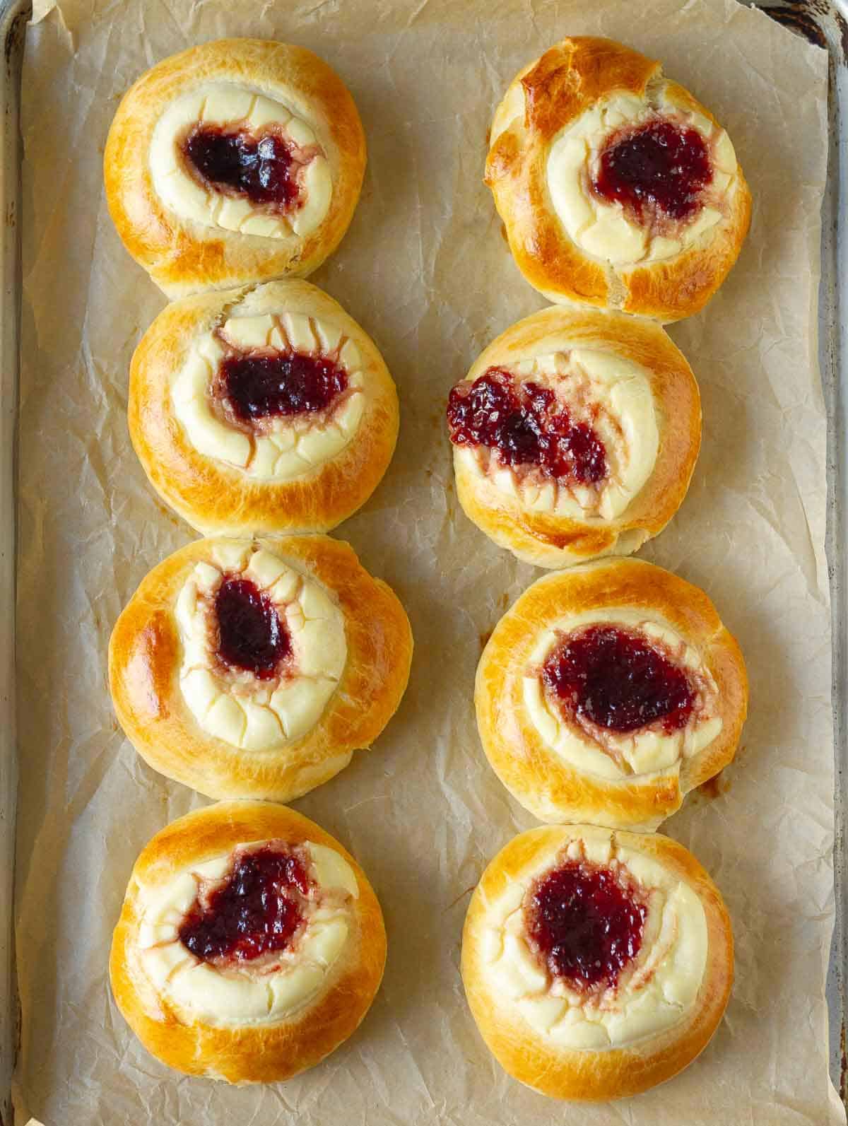 Baked strawberry cream cheese rolls on a paper-lined baking tray.