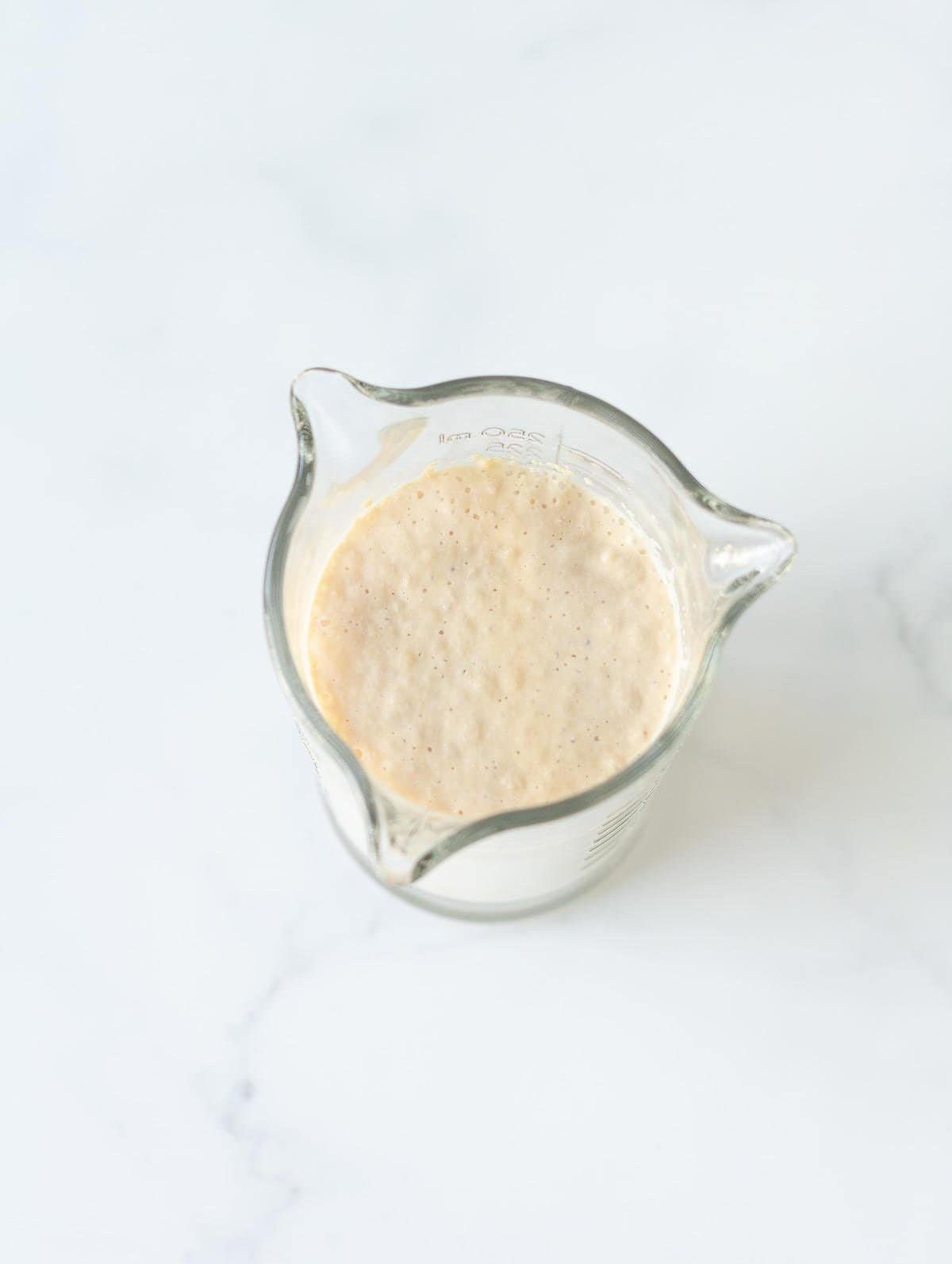 Frothy milk and yeast mixture in a measuring cup.