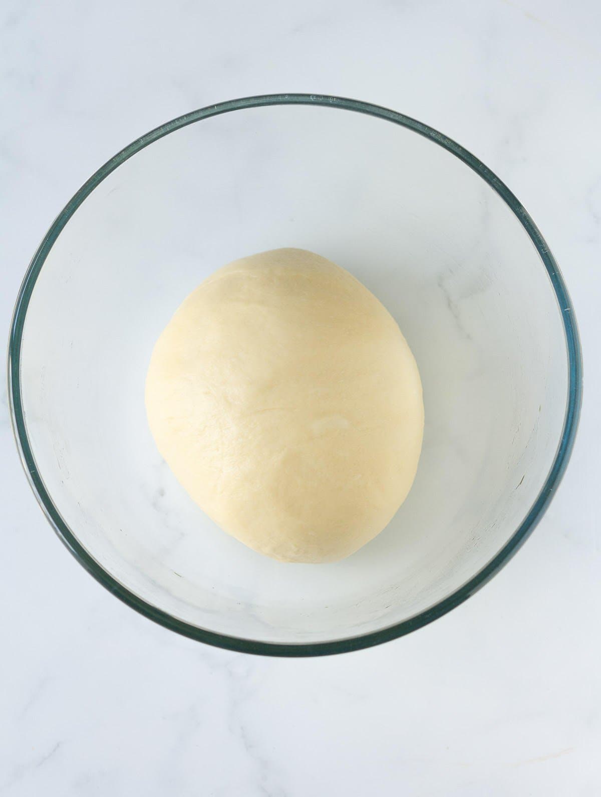 Brioche dough in a glass mixing bowl.