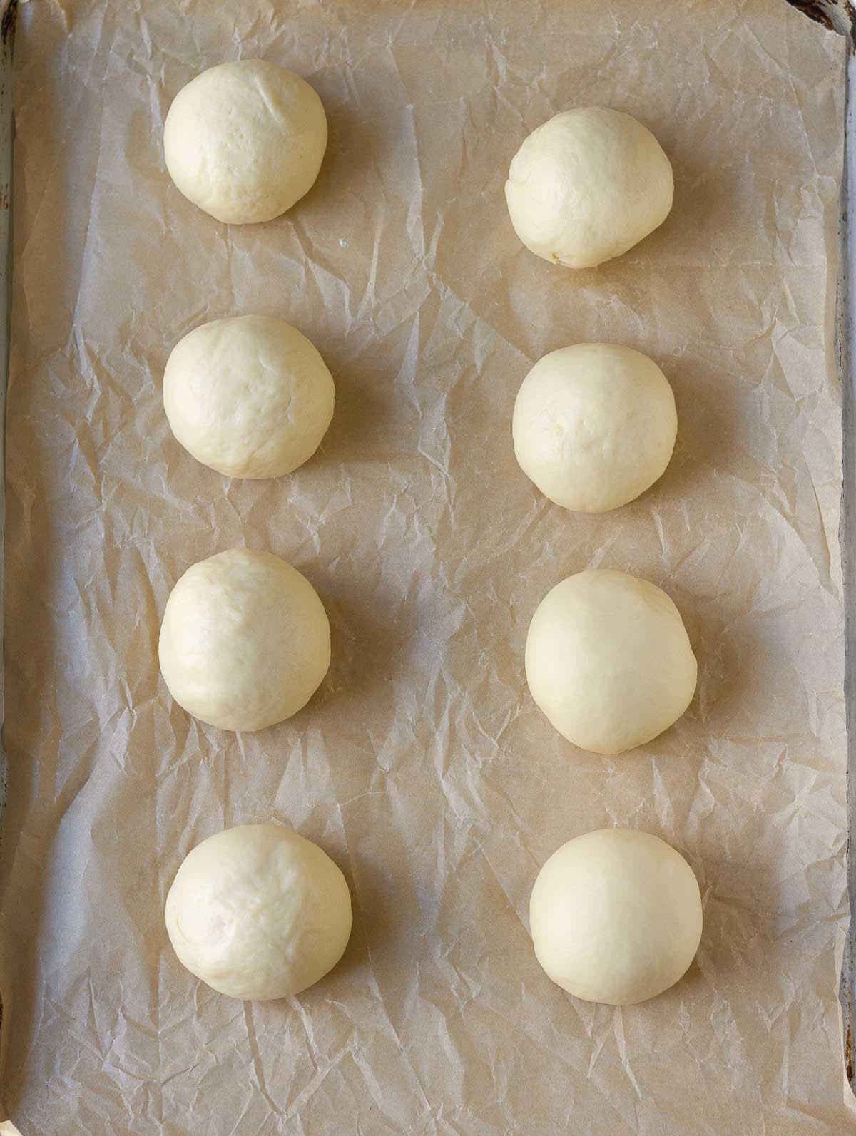 8 dough balls on a paper-lined baking tray.