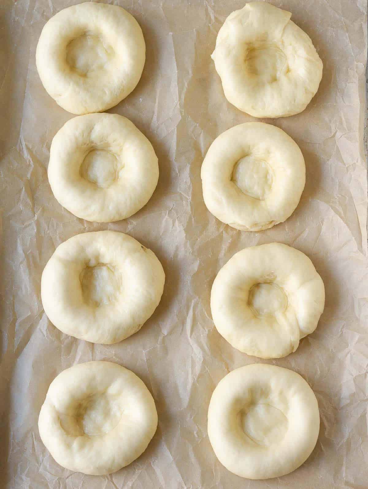 Dough balls with indents in the center on a baking tray.