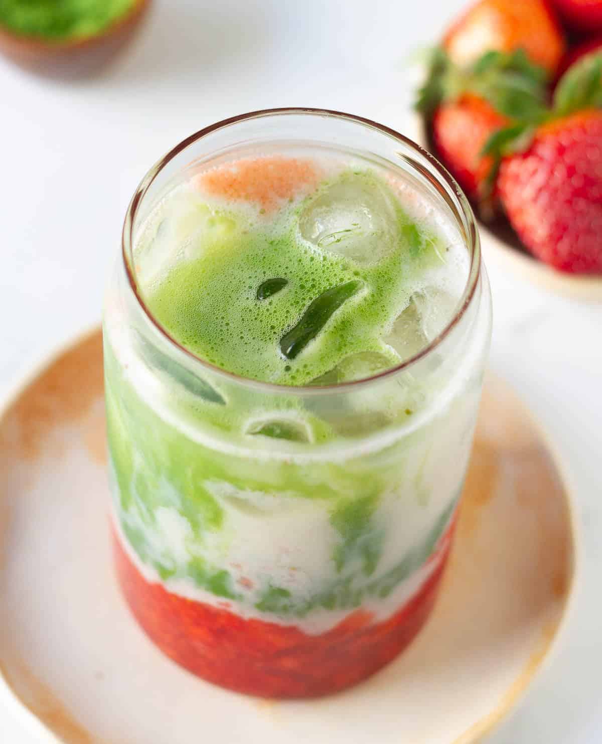 matcha latte with strawberries in a glass with ice.