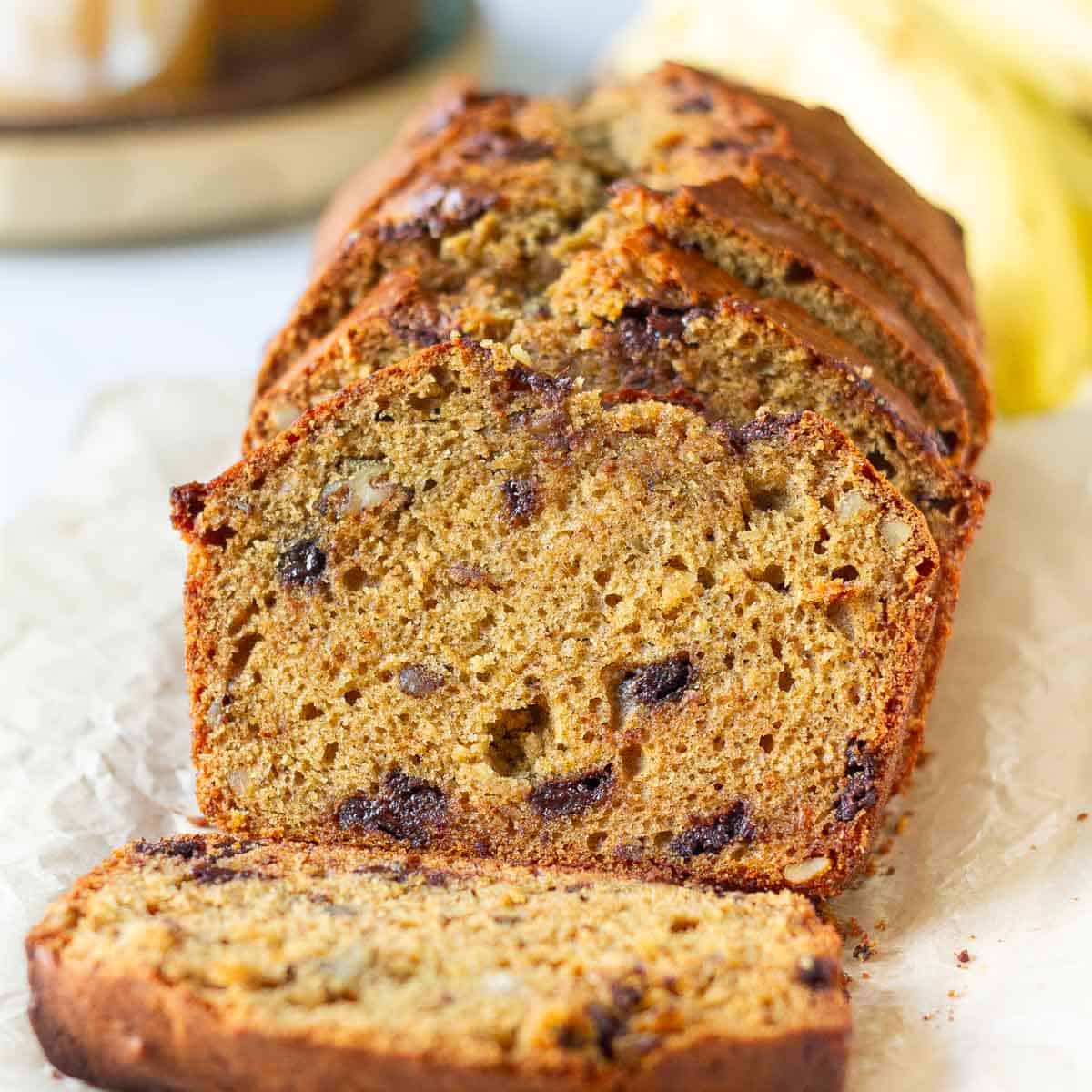 sliced sourdough banana bread with ingredients in the background.