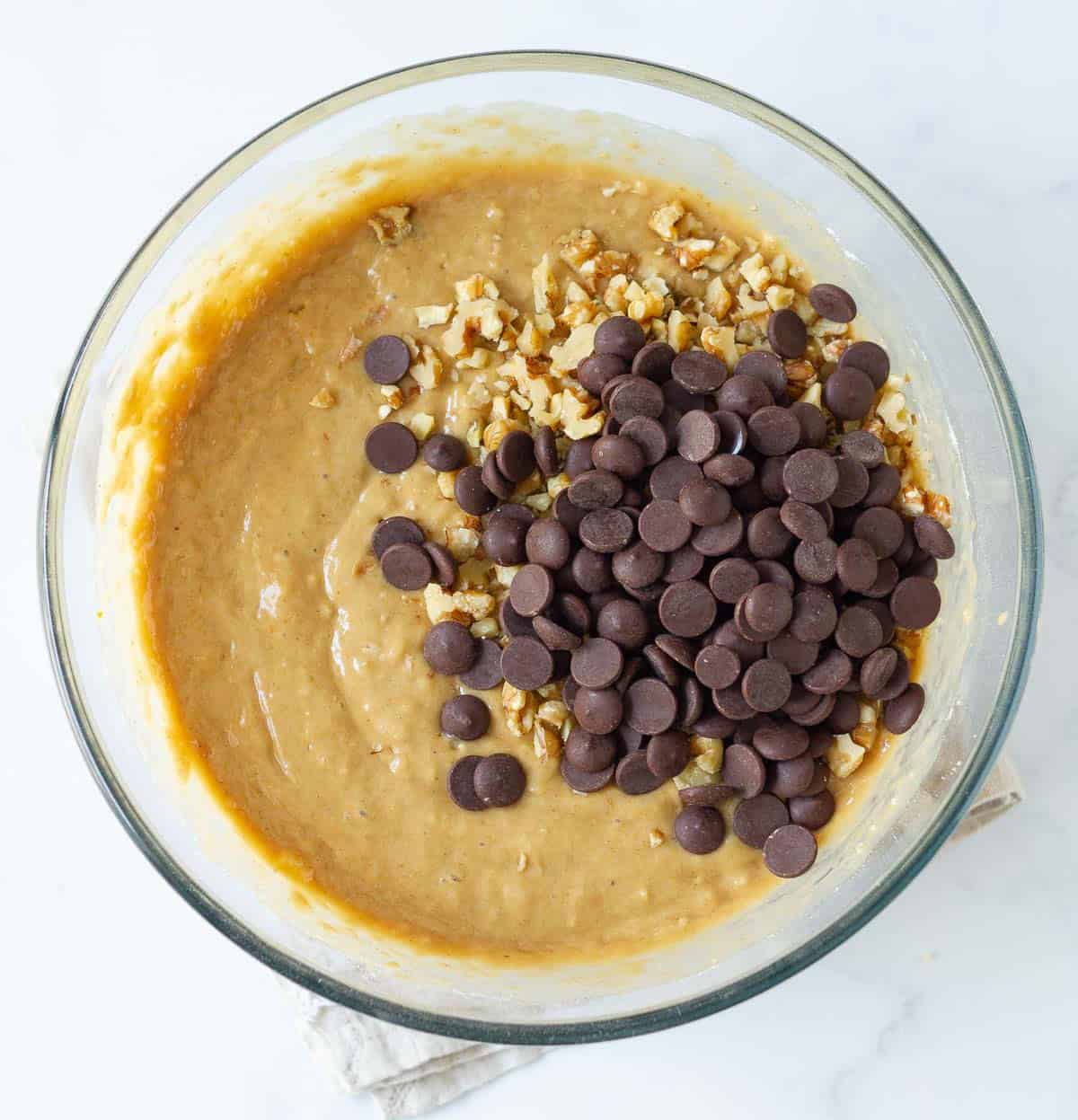 Chopped walnuts and chocolate chips on top of banana bread batter.