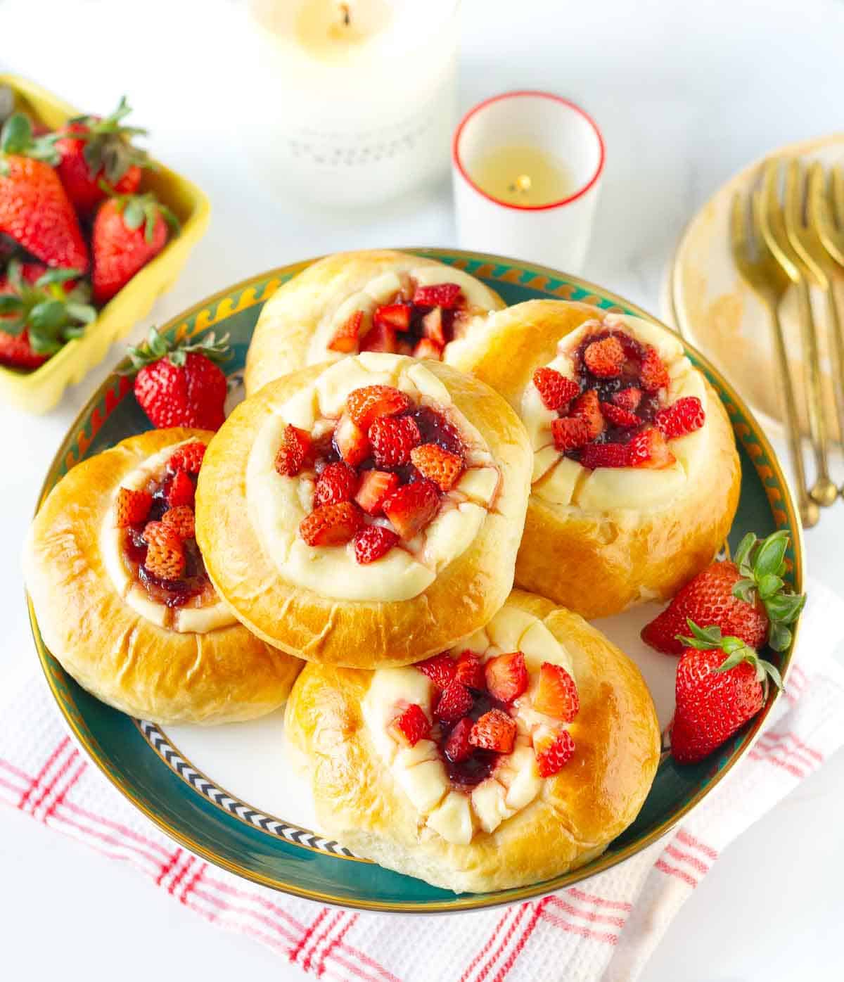 strawberry buns on a cake stand with ingredients and props in the background.