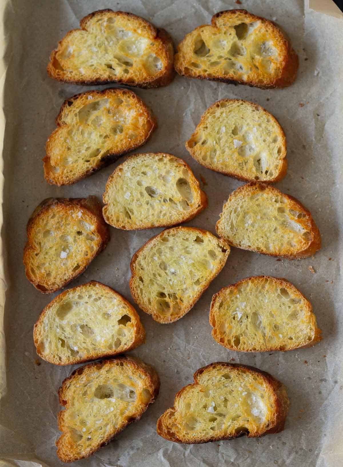 Toasted baguette on a parchment-lined tray.