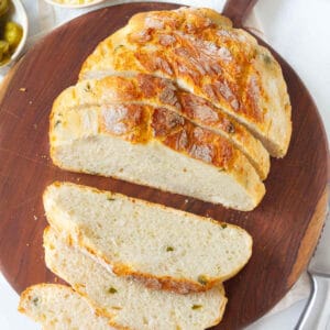 Sliced loaf of jalapeño cheddar bread on a wooden board.