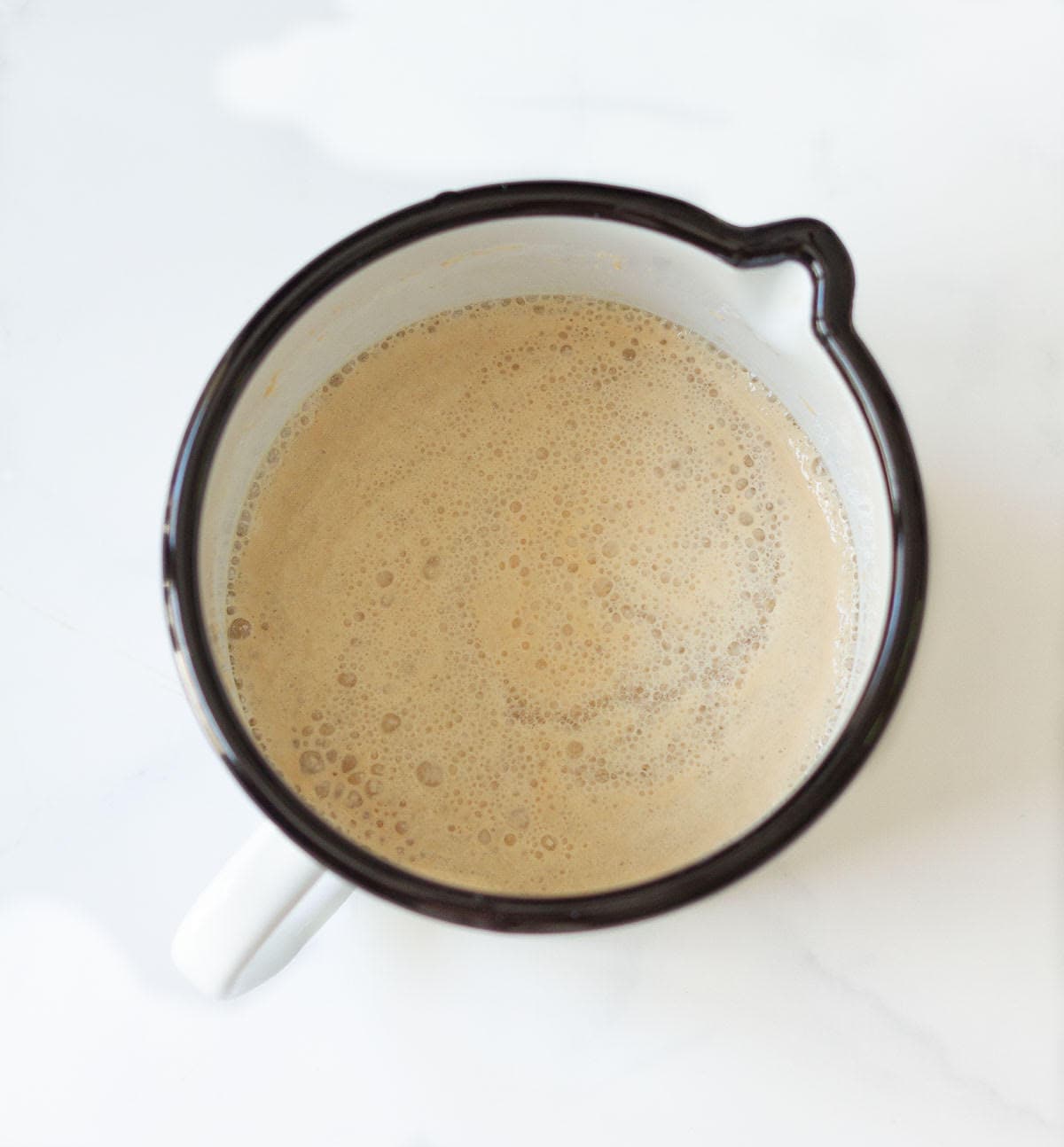 Bubbling and frothy yeast and water mixture in a cup.