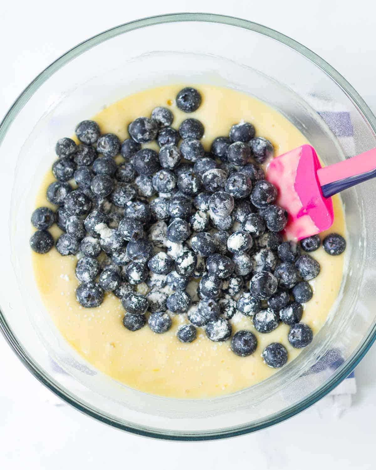 Flour-tossed blueberries on the cake batter in a bowl.
