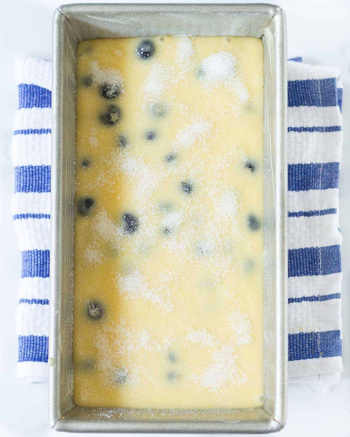Blueberry and lemon bread batter sprinkled with sugar in a loaf pan.