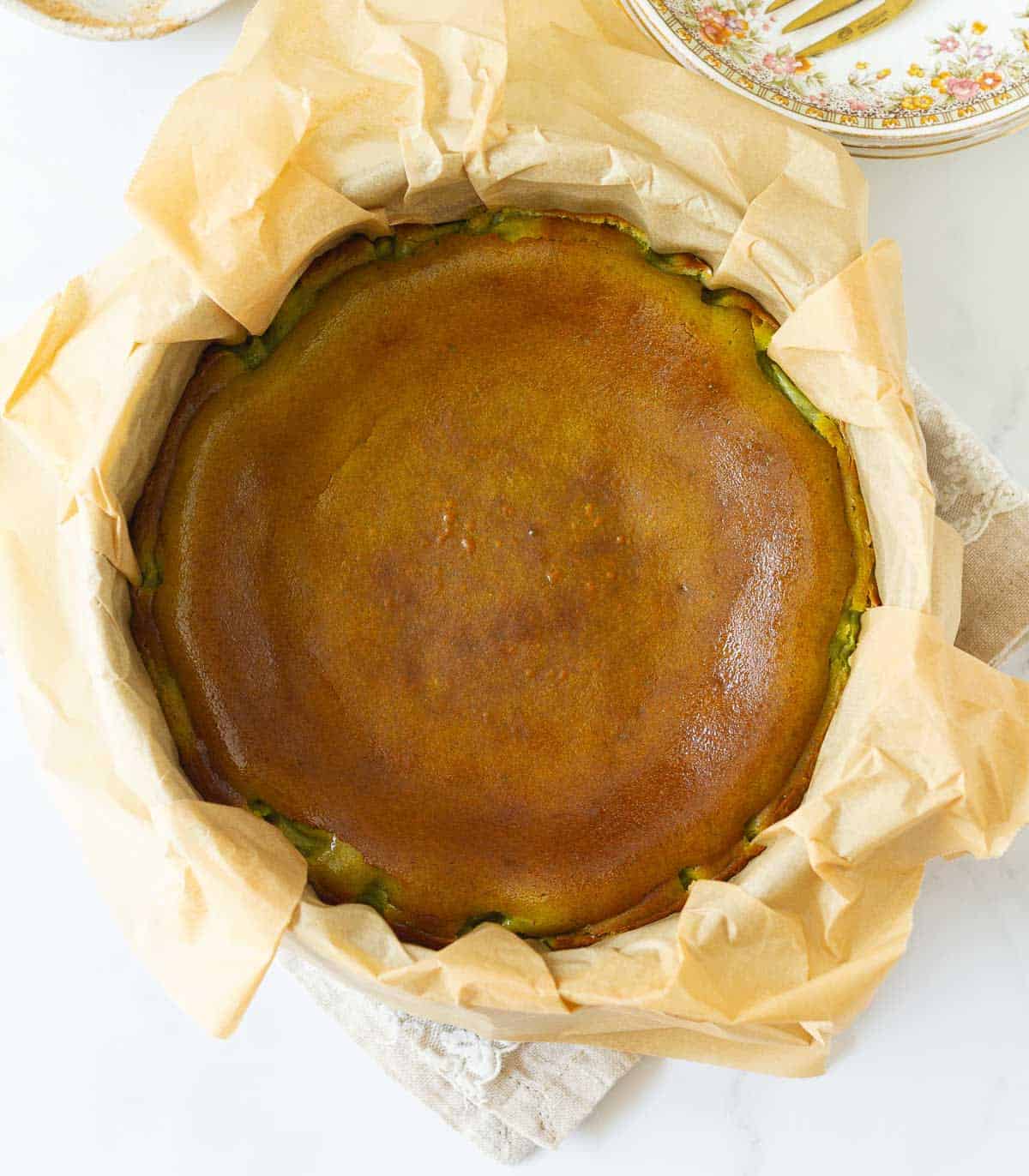 baked matcha basque cheesecake in a parchment paper lined cake pan.