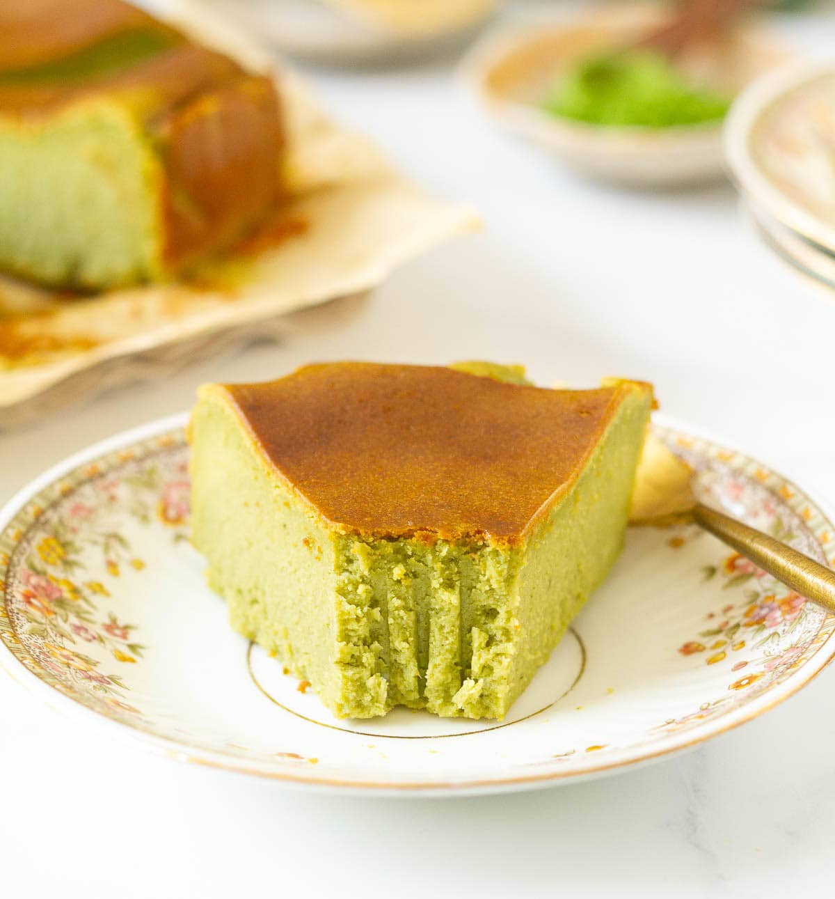 A slice of cheesecake on a small plate with a bite taken.