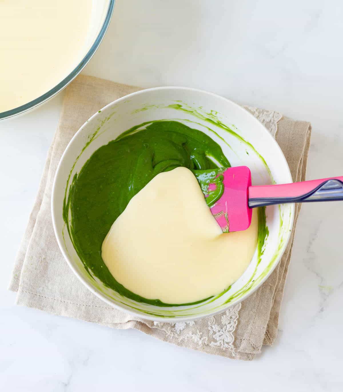 Cheesecake batter with matcha cheesecake batter in a bowl.