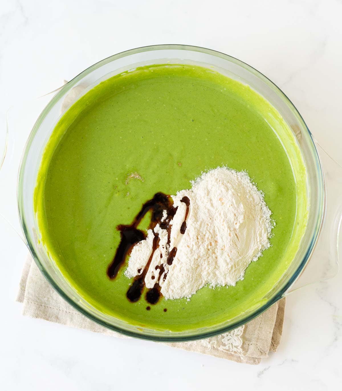 Flour, salt, and vanilla extract on top of matcha cheesecake batter.