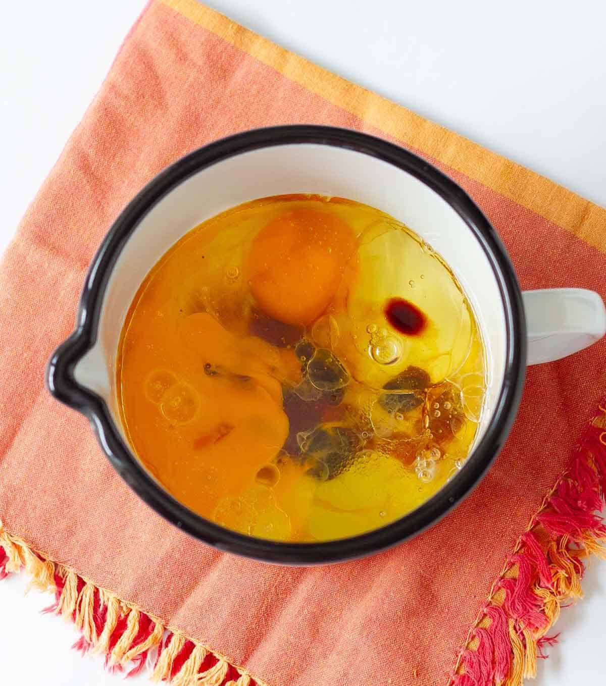 Eggs, oil, vanilla extract in a cup.