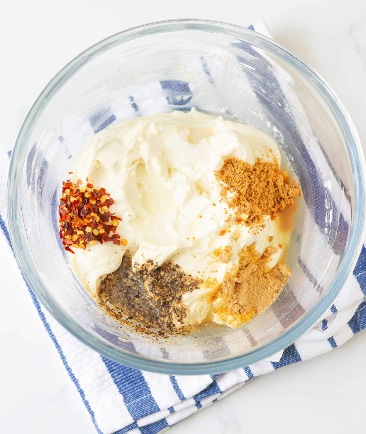 Seasoning and spices on cream cheese mixture in a mixing bowl.