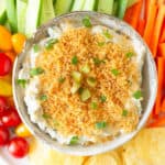 Fried pickle dip in a serving bowl with veggies and chips around.