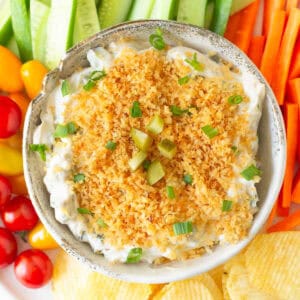 Fried pickle dip in a serving bowl with veggies and chips around.