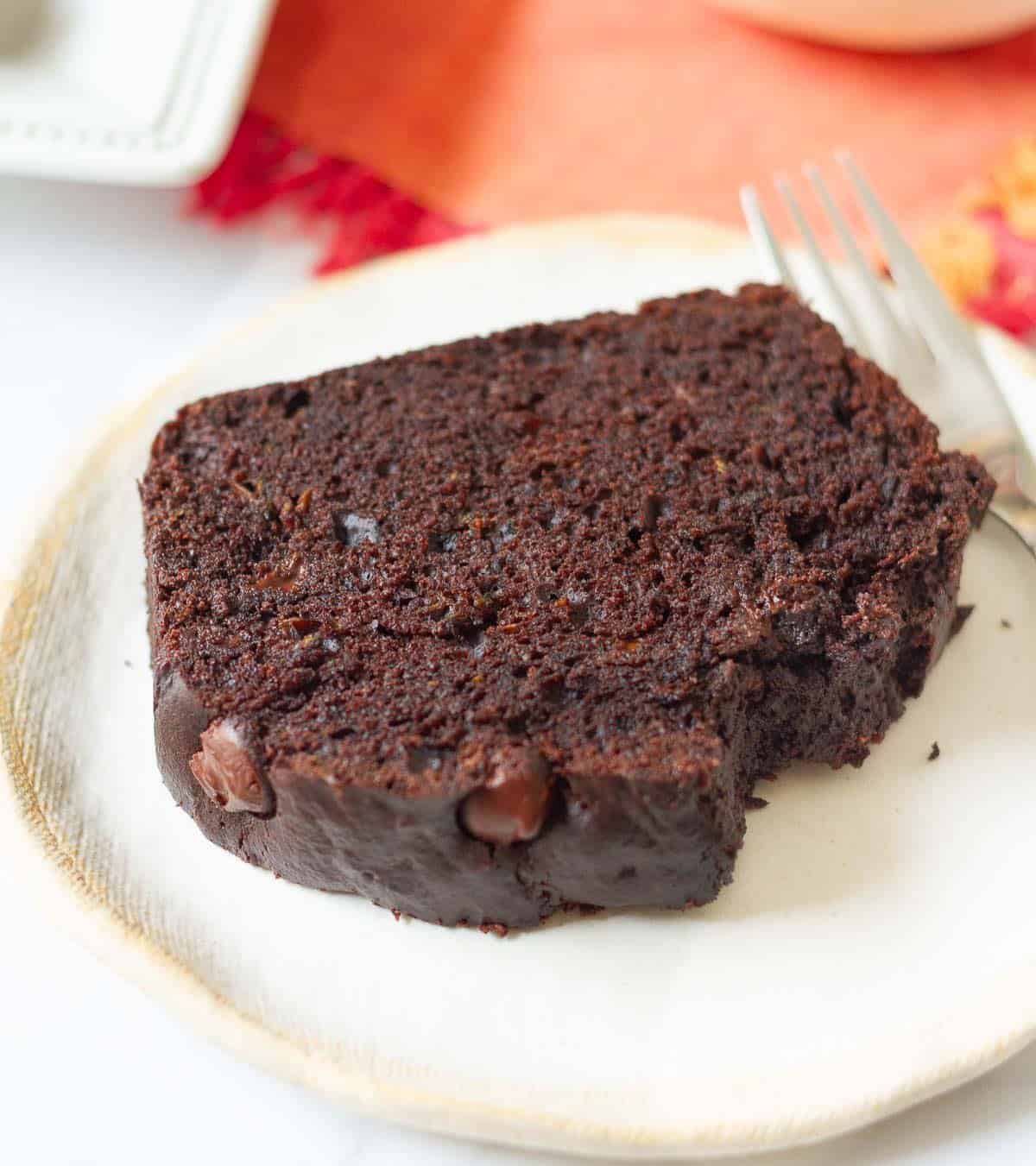A slice of chocolate zucchini bread on a small plate with a fork.