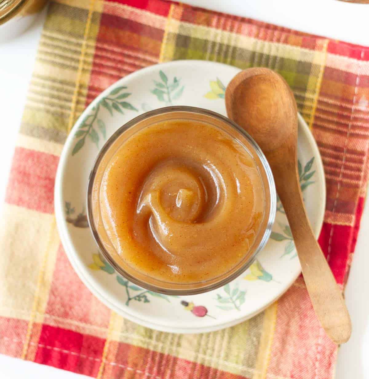Pear butter in a small glass jar with a wooden spoon on the side.