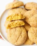 2 halves of a cookie with more cookies on a plate.