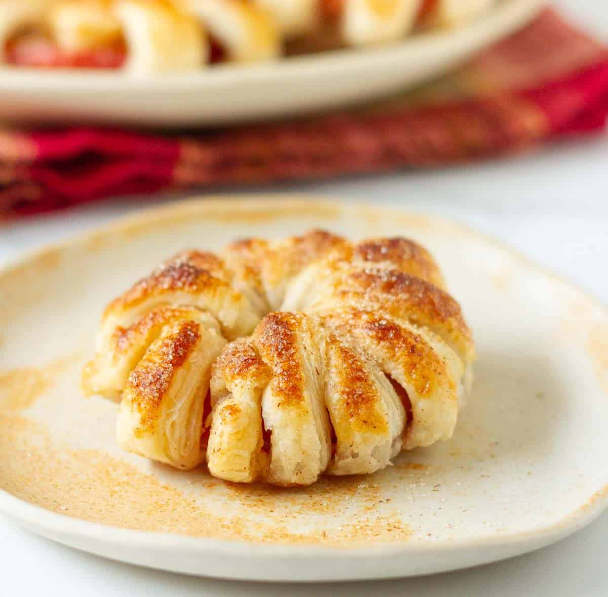 A puff pastry apple donut on a small plate.