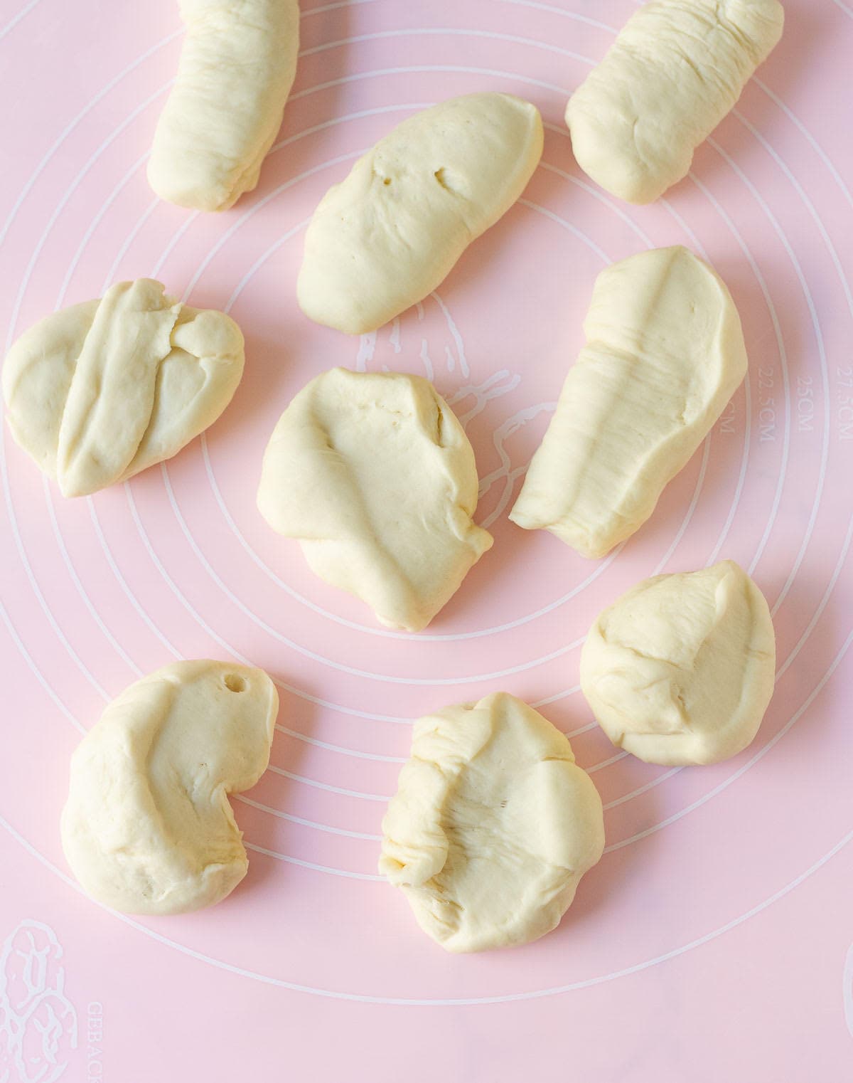 Bread dough divided into pieces on a silicone mat.