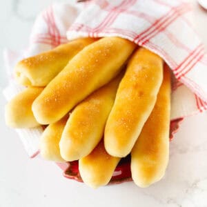 Garlic breadsticks wrapped in a red and white kitchen napkin.