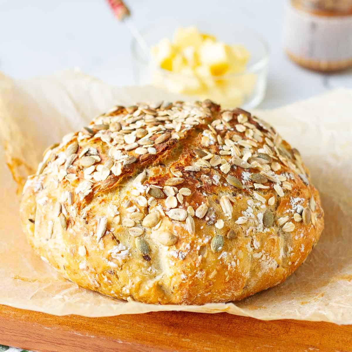 no knead seeded oatmeal bread loaf on parchment paper.