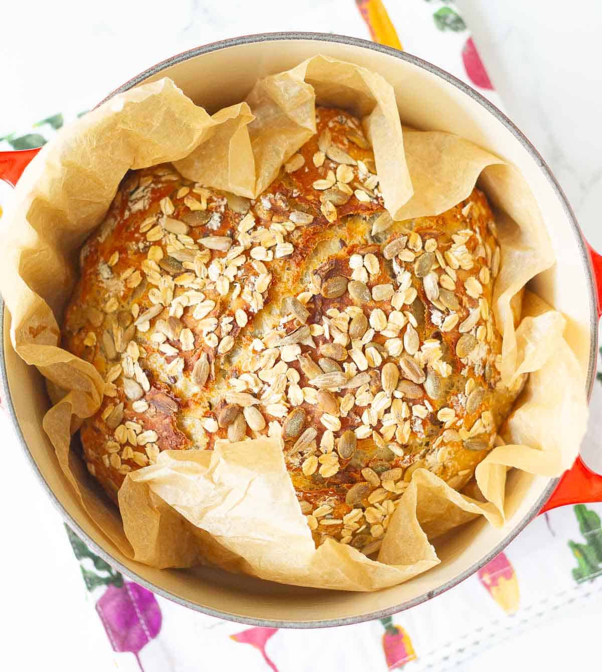 baked bread on parchment paper in a dutch oven.