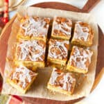 Apple fritter cake cut into 9 pieces on parchment paper.