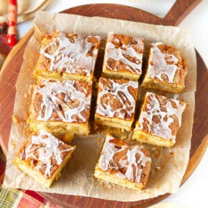Apple fritter cake cut into 9 pieces on parchment paper.