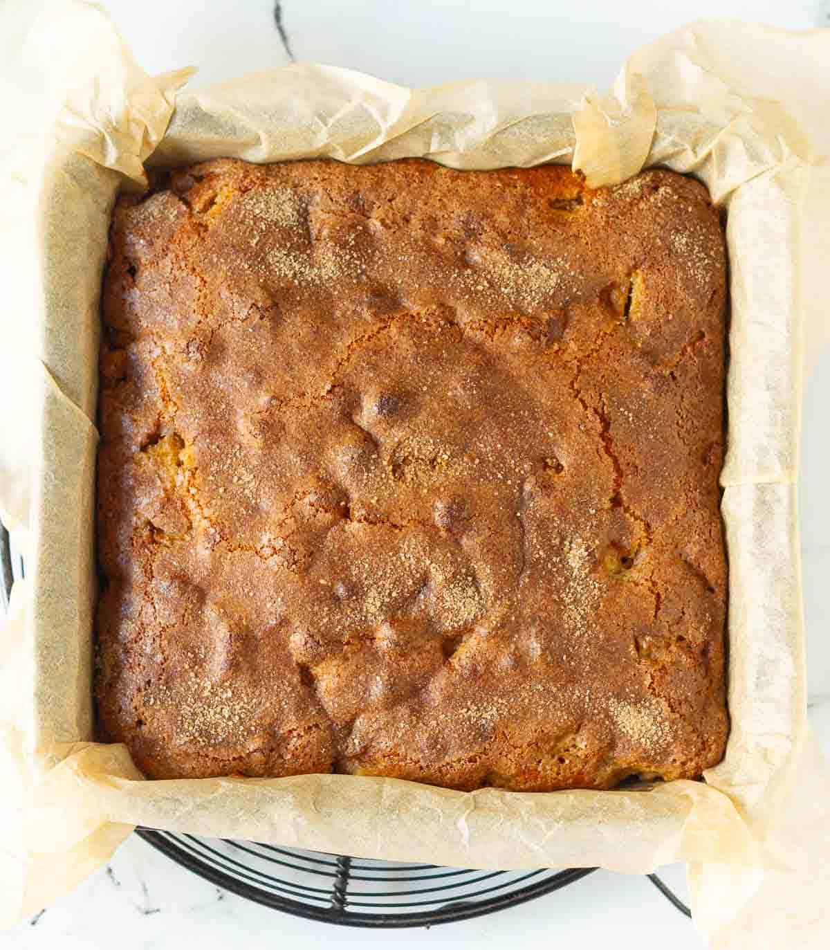 Baked cake in a parchment lined cake pan.