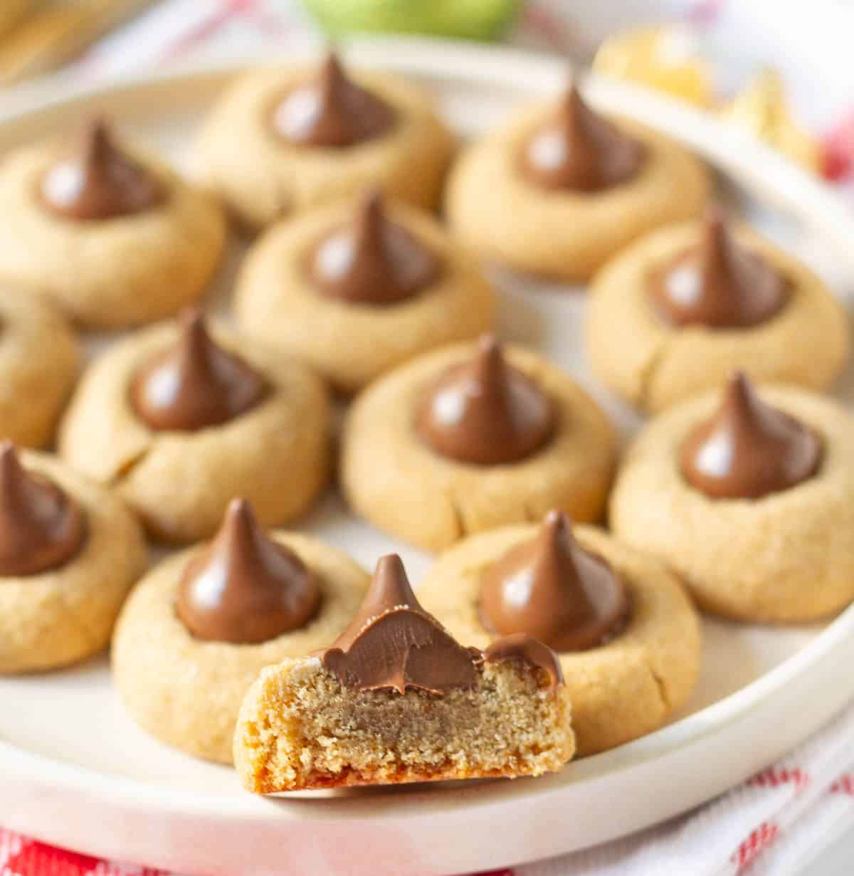 Cookies topped with Hershey's kisses on a platter with one cookie half to show the texture.