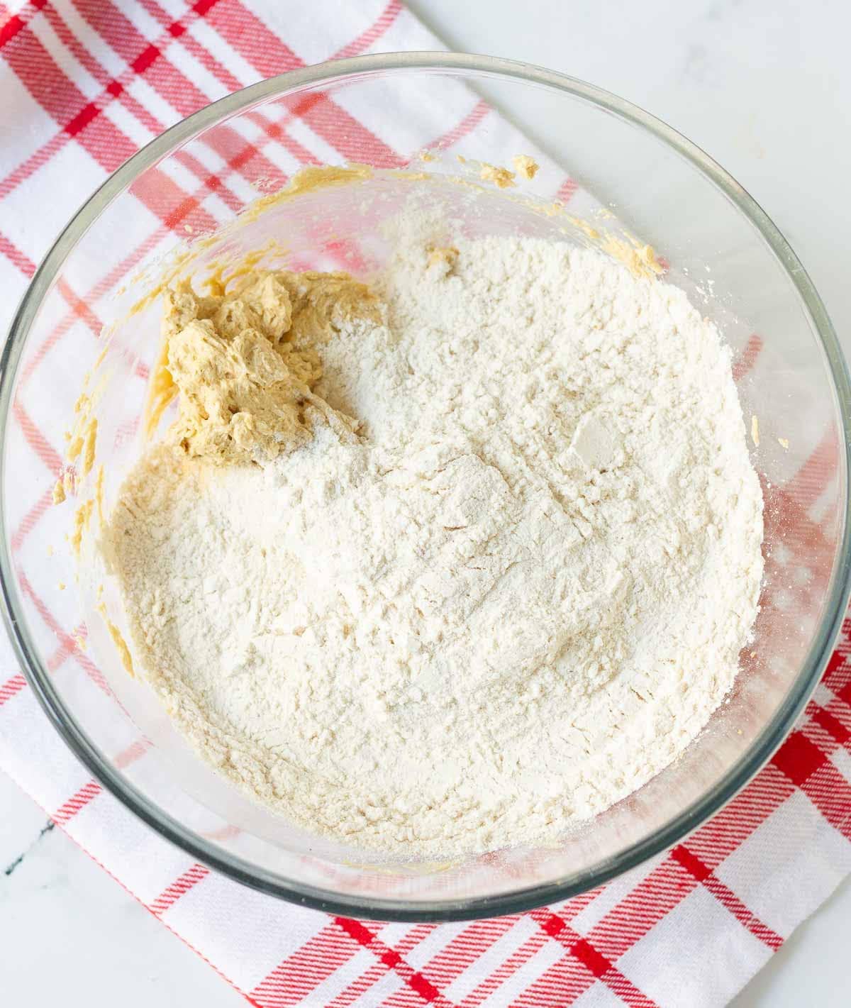 Flour on top of buuter-sugar mixture in a mixing bowl.