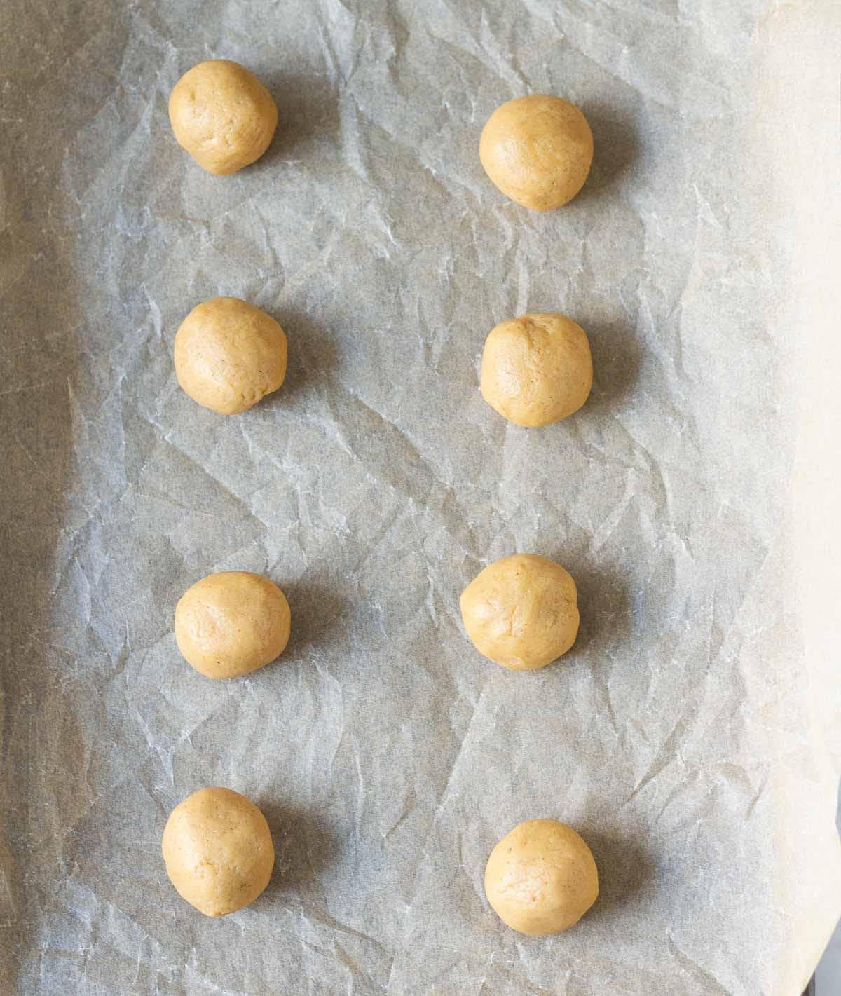 Cookie dough balls on parchment paper.