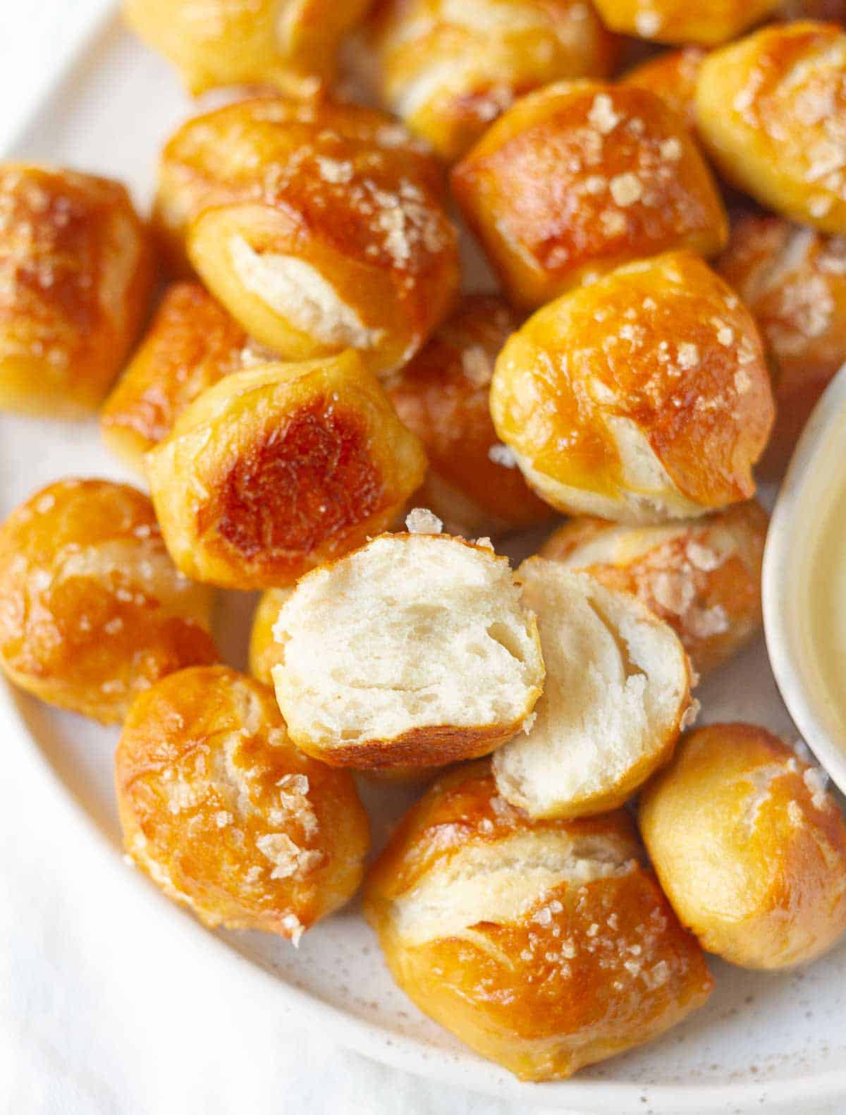 A platter with pretzel bites with one bite cut in half.