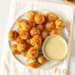 A platter full of pretzel bites and a bowl of dipping sauce.