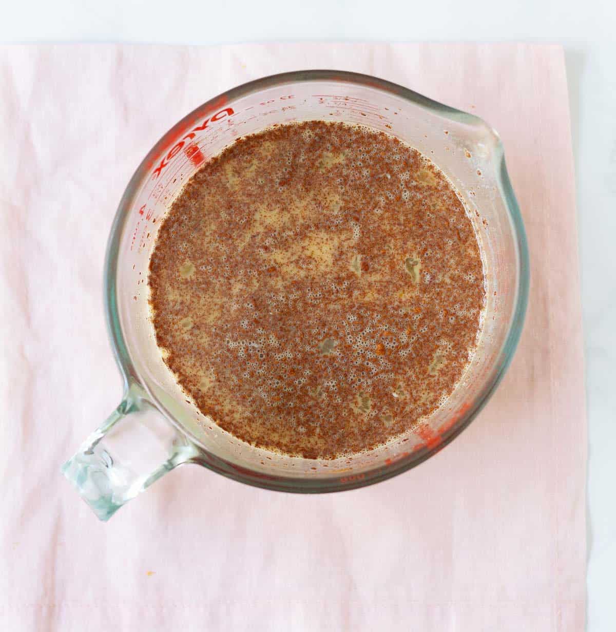 A mixture of eggs, milk, sugar, and cinnamon powder in a measuring cup.