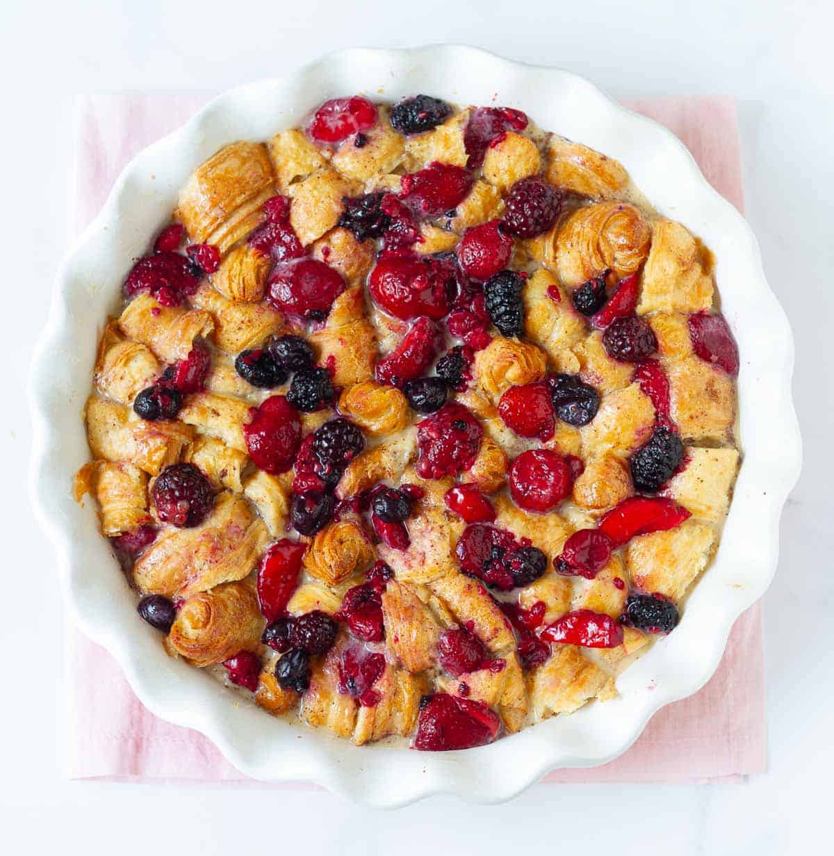 Cut up croissants and berries in a baking dish.