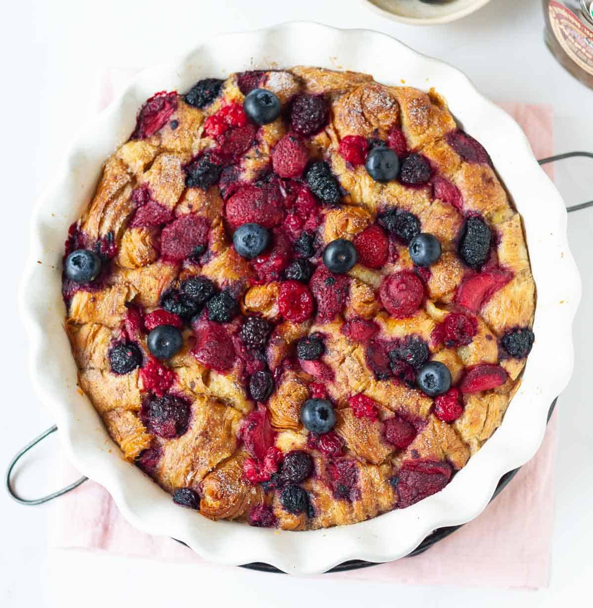 Baked croissant and berries casserole in a baking dish.