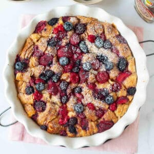 Baked croissant and berries casserole with powdered sugar on top.