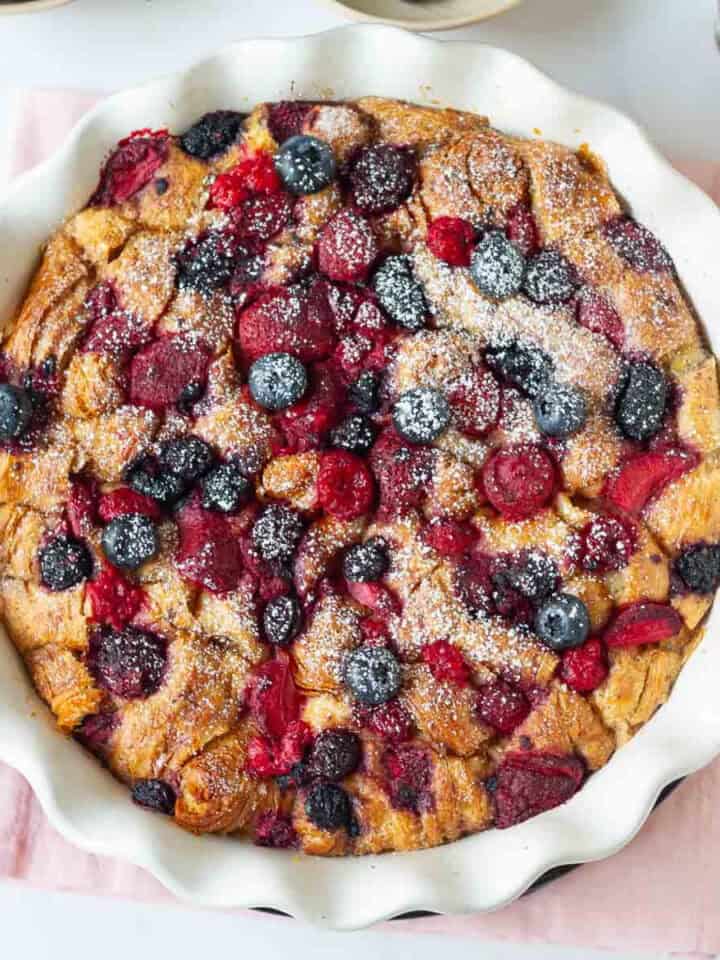 Baked croissant and berries casserole with powdered sugar on top.
