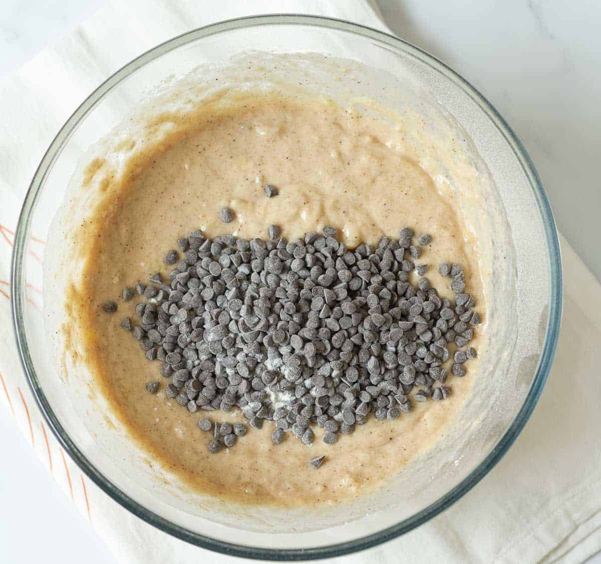 Flour-coated chocolate chips on top of cake batter in a mixing bowl.