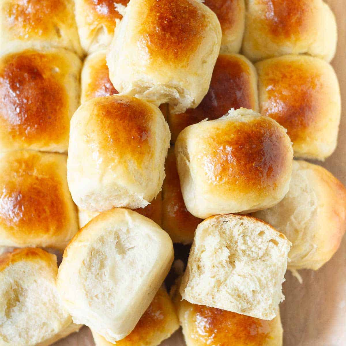 A pile of dinner rolls with half a roll on top to show the cross-section.