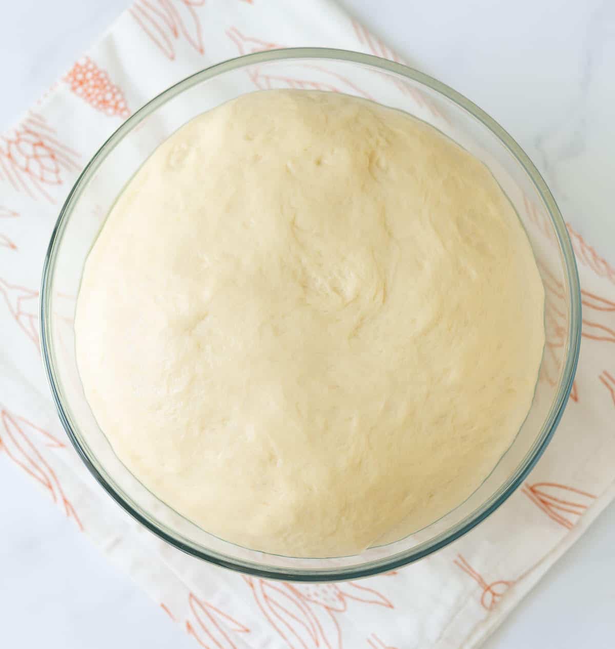 Proofed bread dough in a glass bowl.