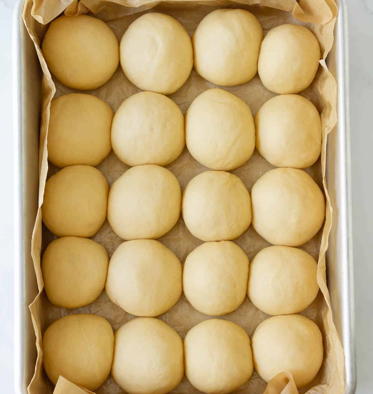 Dough balls in a parchment paper-lined baking dish.