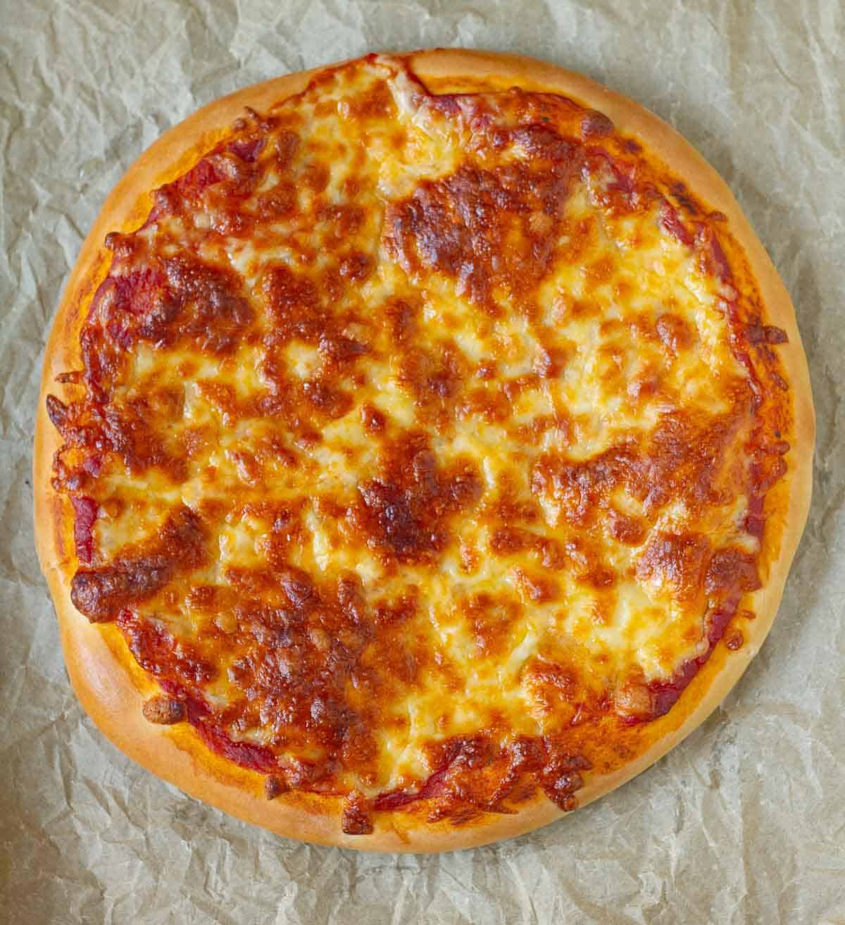 Baked cheese pizza on parchment paper.