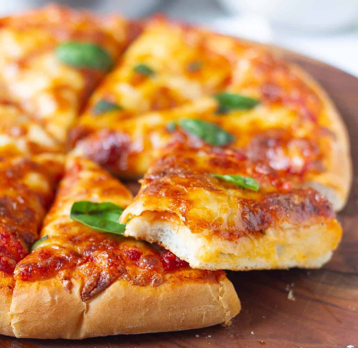 A half eaten pizza slice on top of pizza to show the crust texture.
