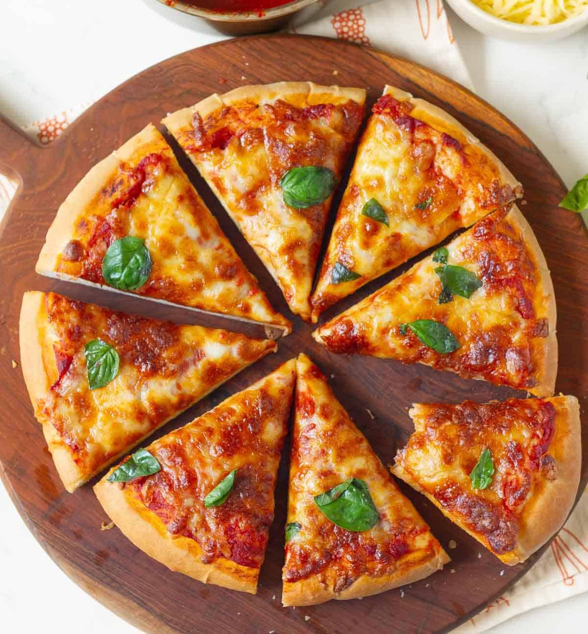 Sliced pizza with one half eaten slice on a wooden board.